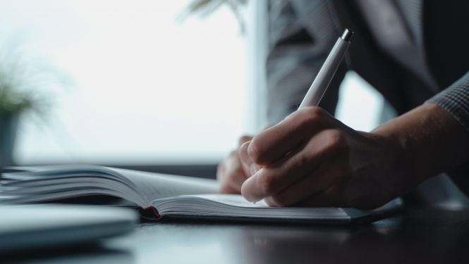 Roka tuvplānā, kas paraksta dokumentu