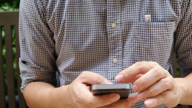 Vīrietis ar mobilo telefonu rokās