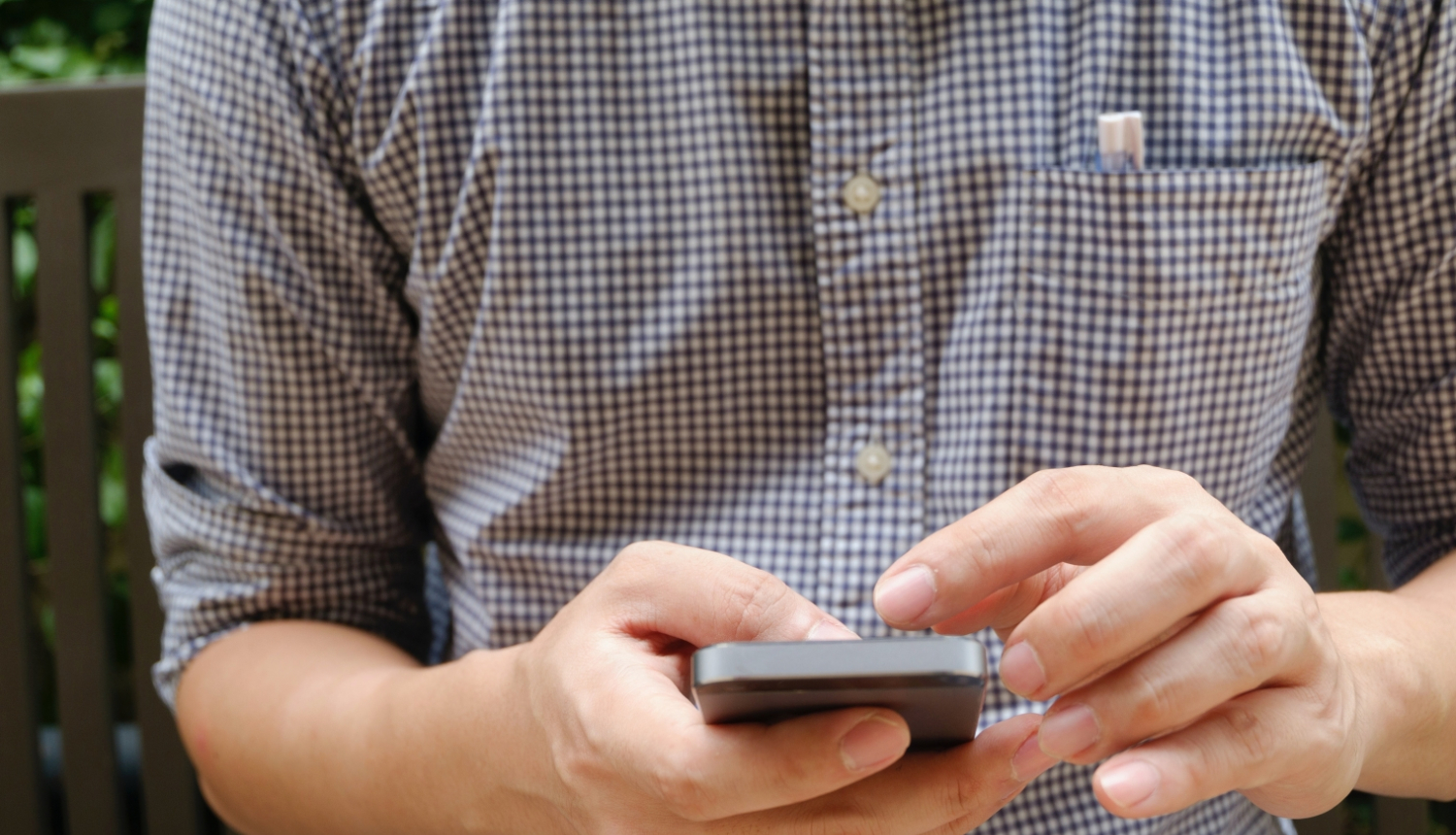 Vīrietis ar mobilo telefonu rokās